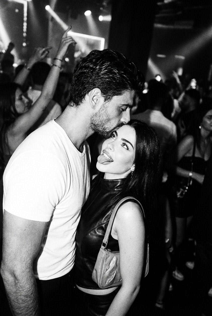 Cinematic close-up of a rebellious couple kissing, one in a t-shirt, the other in a sleeveless leather top, playful expression.