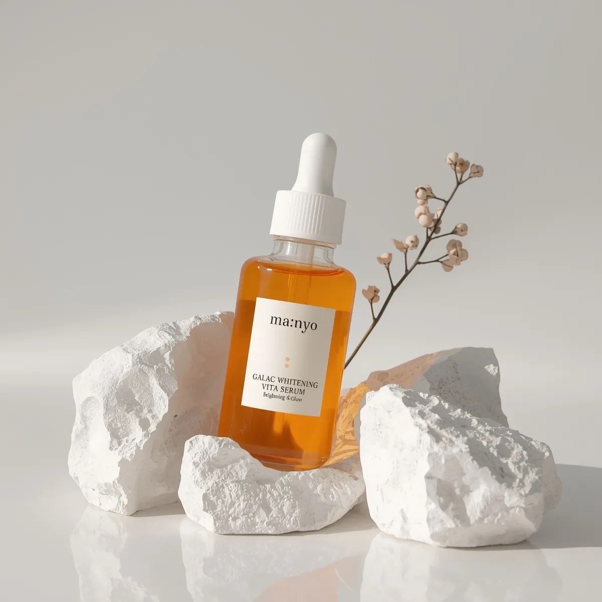 Amber glass dropper serum bottle nestled among textured white stones in soft lighting.