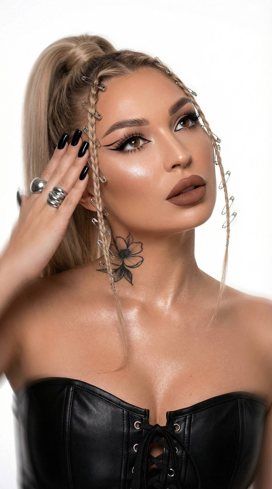 Close-up of an expressive woman with braided hair and shiny makeup in a leather corset, set against a blurred background.