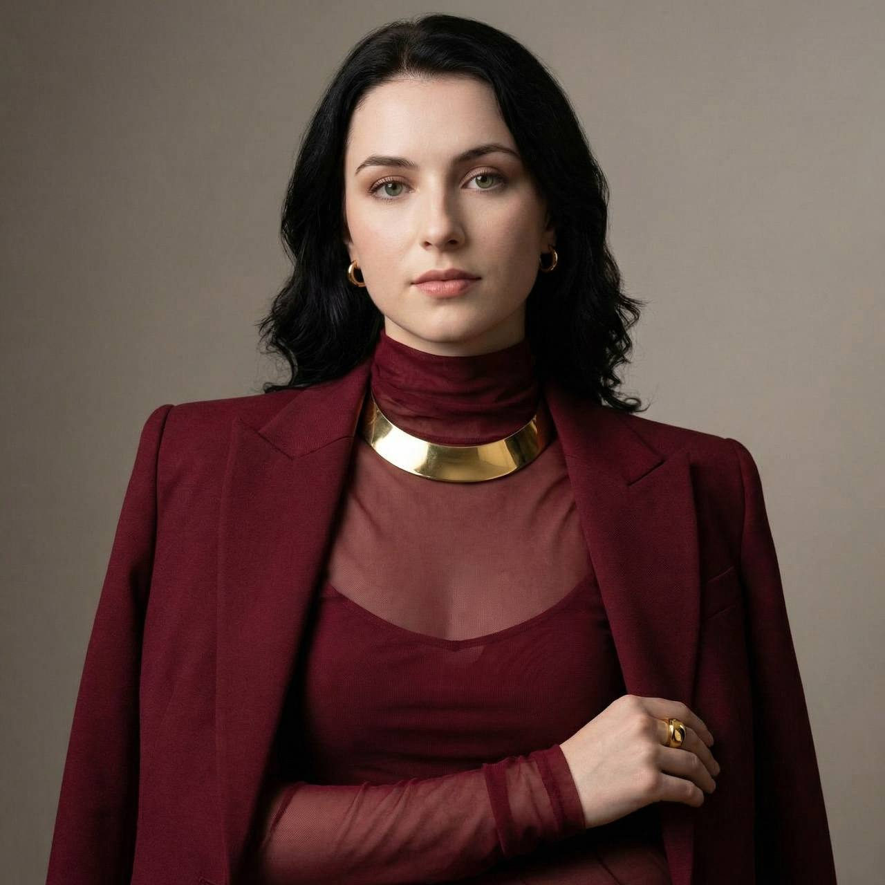 Glamorous model in a burgundy power suit with structured shoulders and sheer blouse.