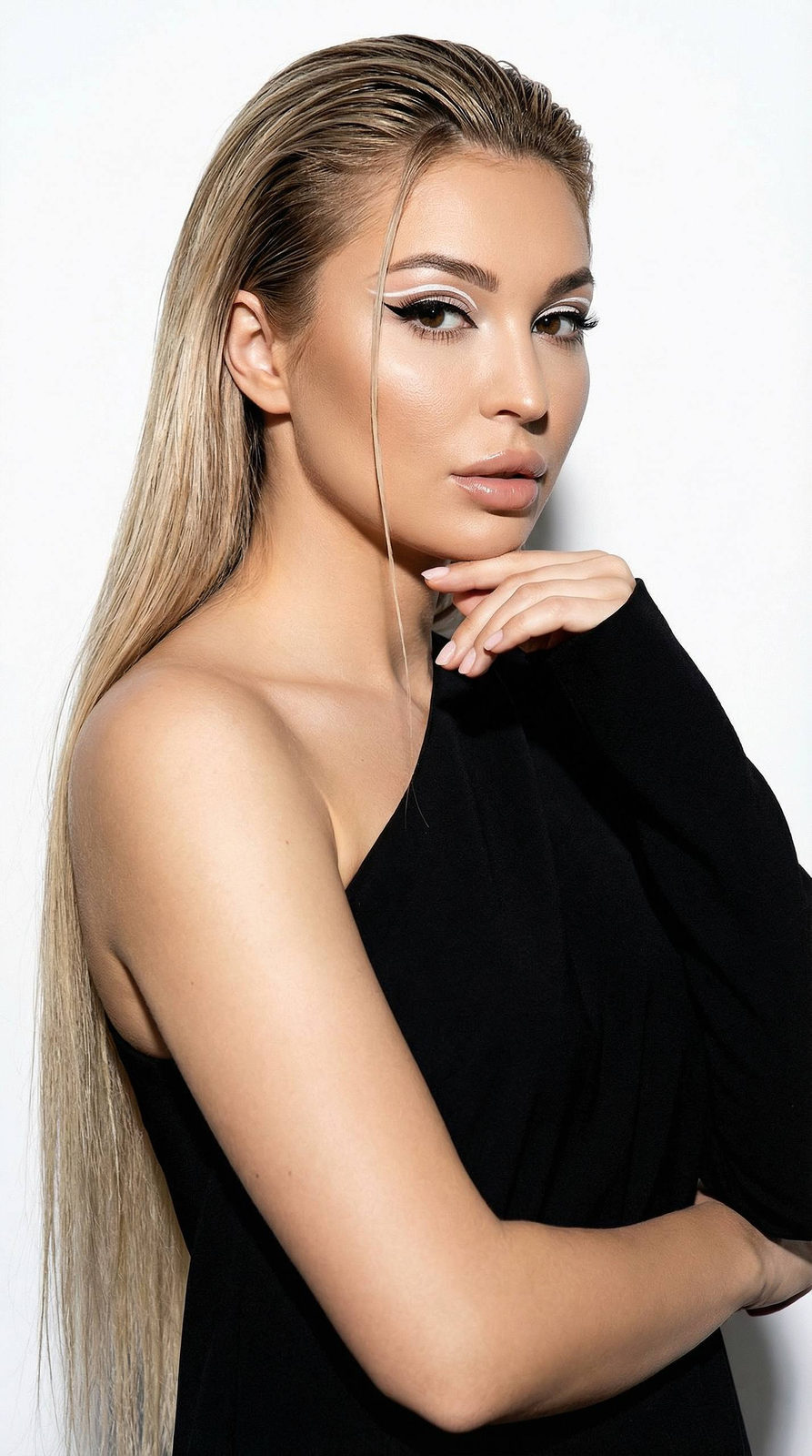 Extreme close-up of a model in a voluminous sack dress showcasing a sharp asymmetrical neckline and smooth, wet hairstyle.