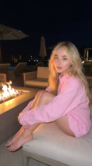 Pink Shirt Outdoor Bench Night Fire Pit Bokeh – A medium shot captures the woman in the uploaded reference image (DO NOT