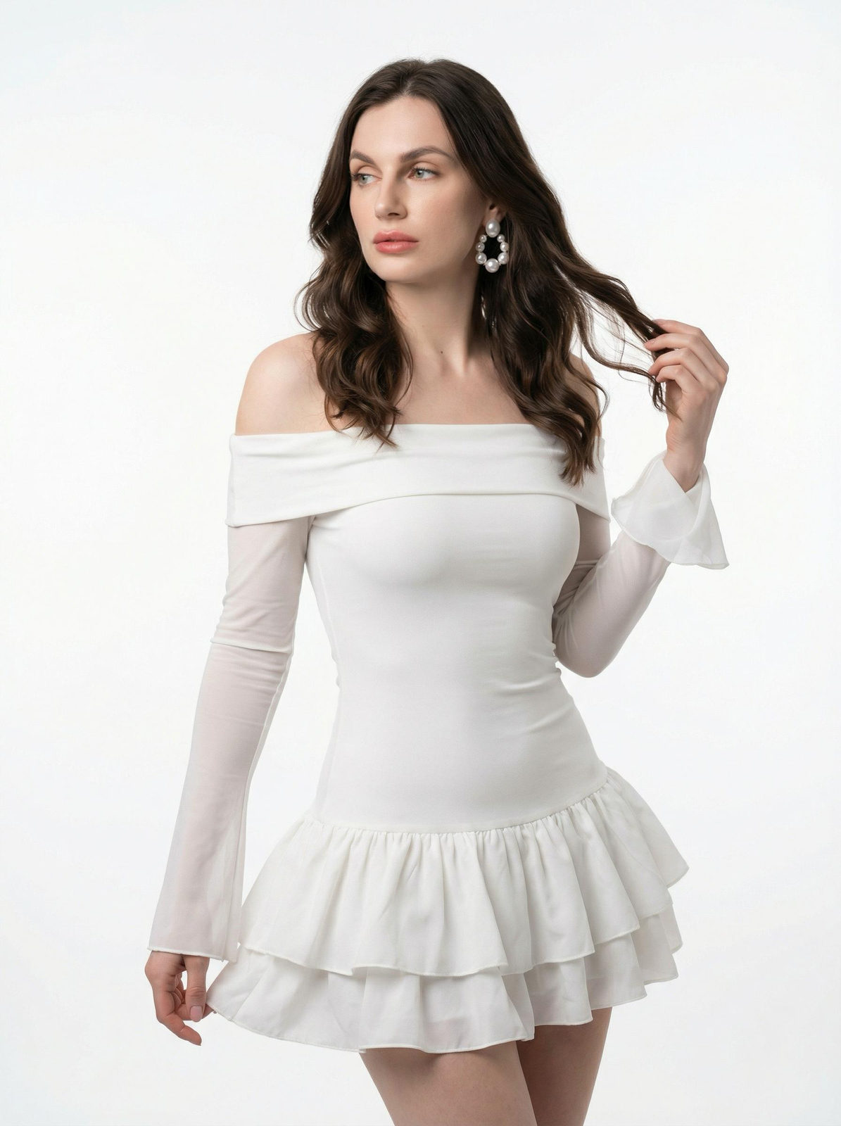 A woman in a white off-the-shoulder dress, softly lit in a studio, gazing away with long waves of glossy hair.