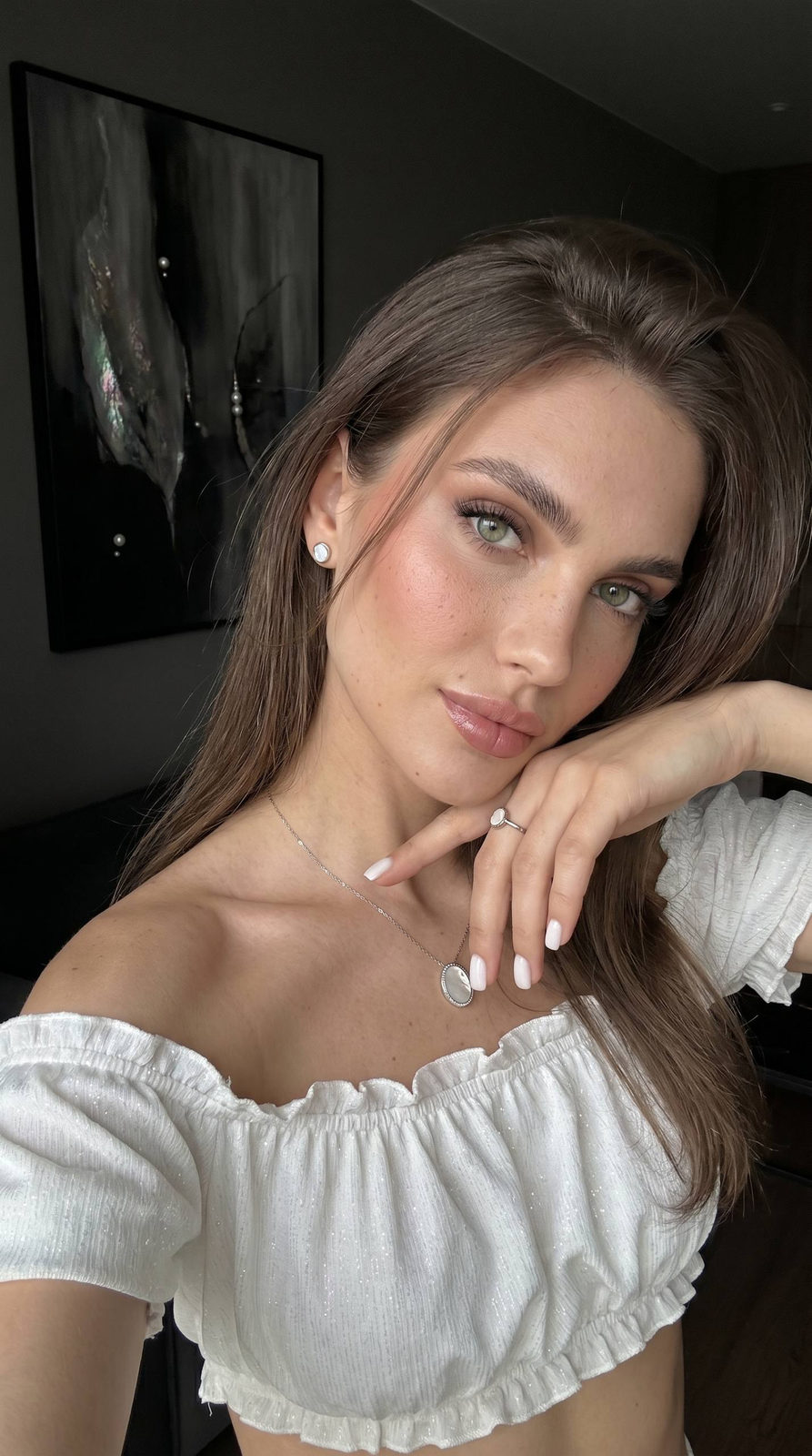 Close-up of a woman with matte skin and peach blush in a modern apartment, tilted head and natural expression.