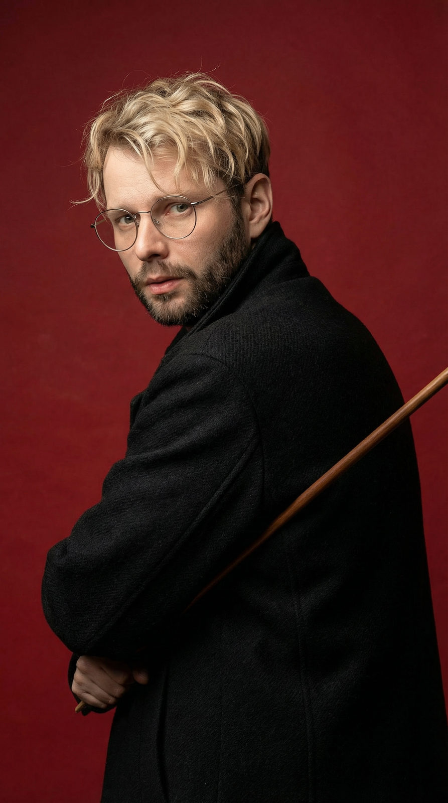 A hyper-realistic fashion portrait of a young person with wavy hair, wearing metal-framed glasses against a deep matte red background.