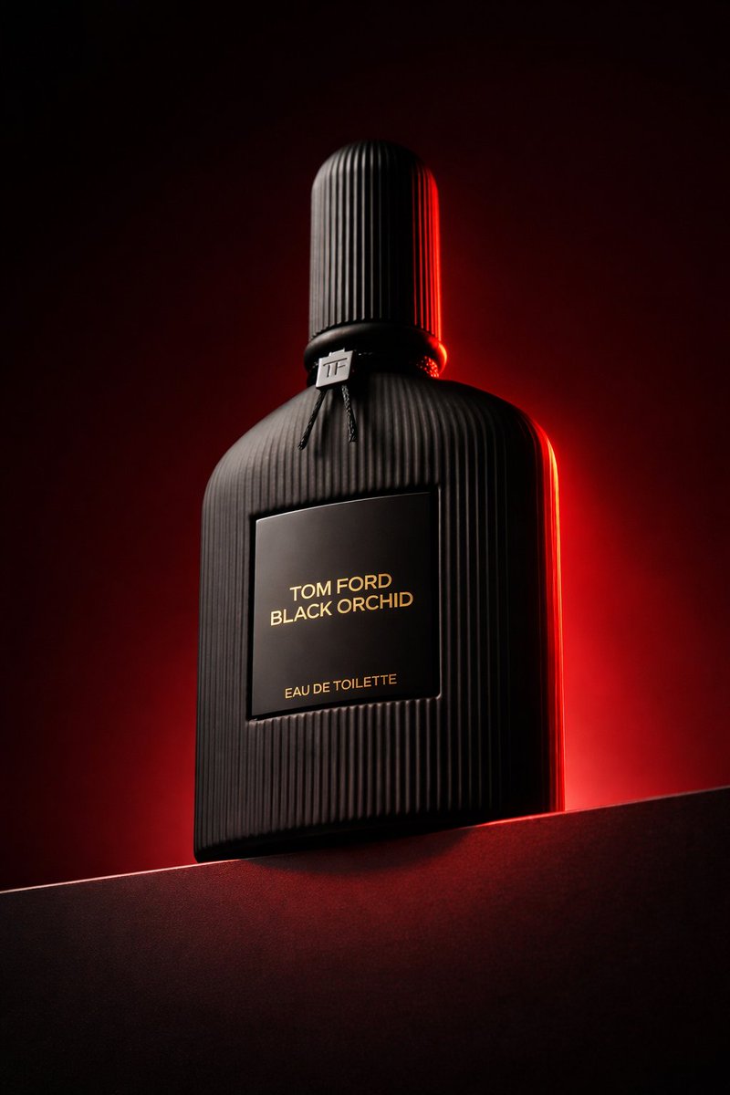 Dramatic low angle shot of Tom Ford Black Orchid perfume bottle on dark podium, highlighting matte texture and red rim light.
