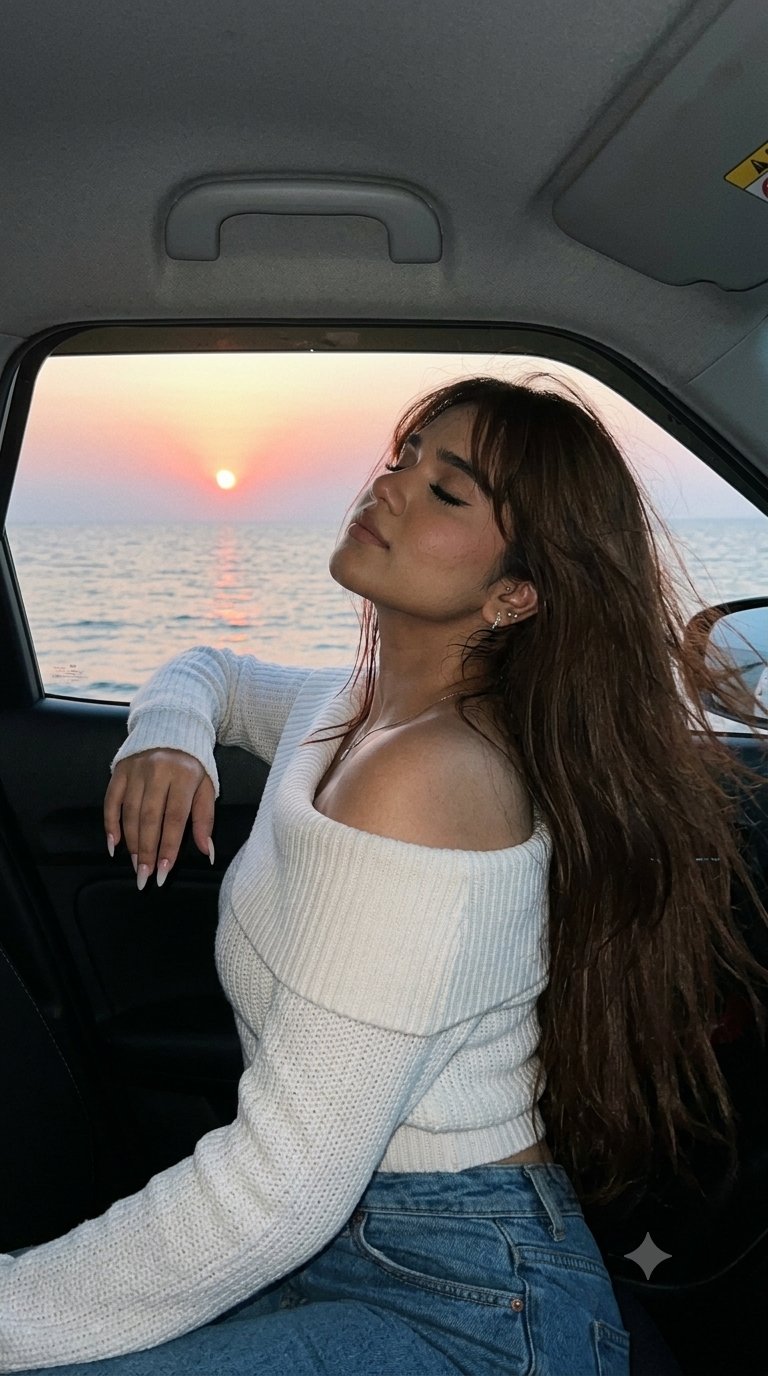 A girl leans out of a car window overlooking the sea at sunset, with long hair fluttering and a relaxed expression.