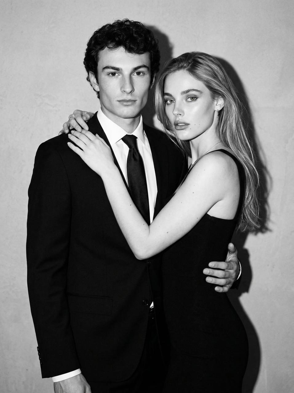 A striking black-and-white portrait of a couple standing closely together against a textured wall, showcasing intricate facial details.