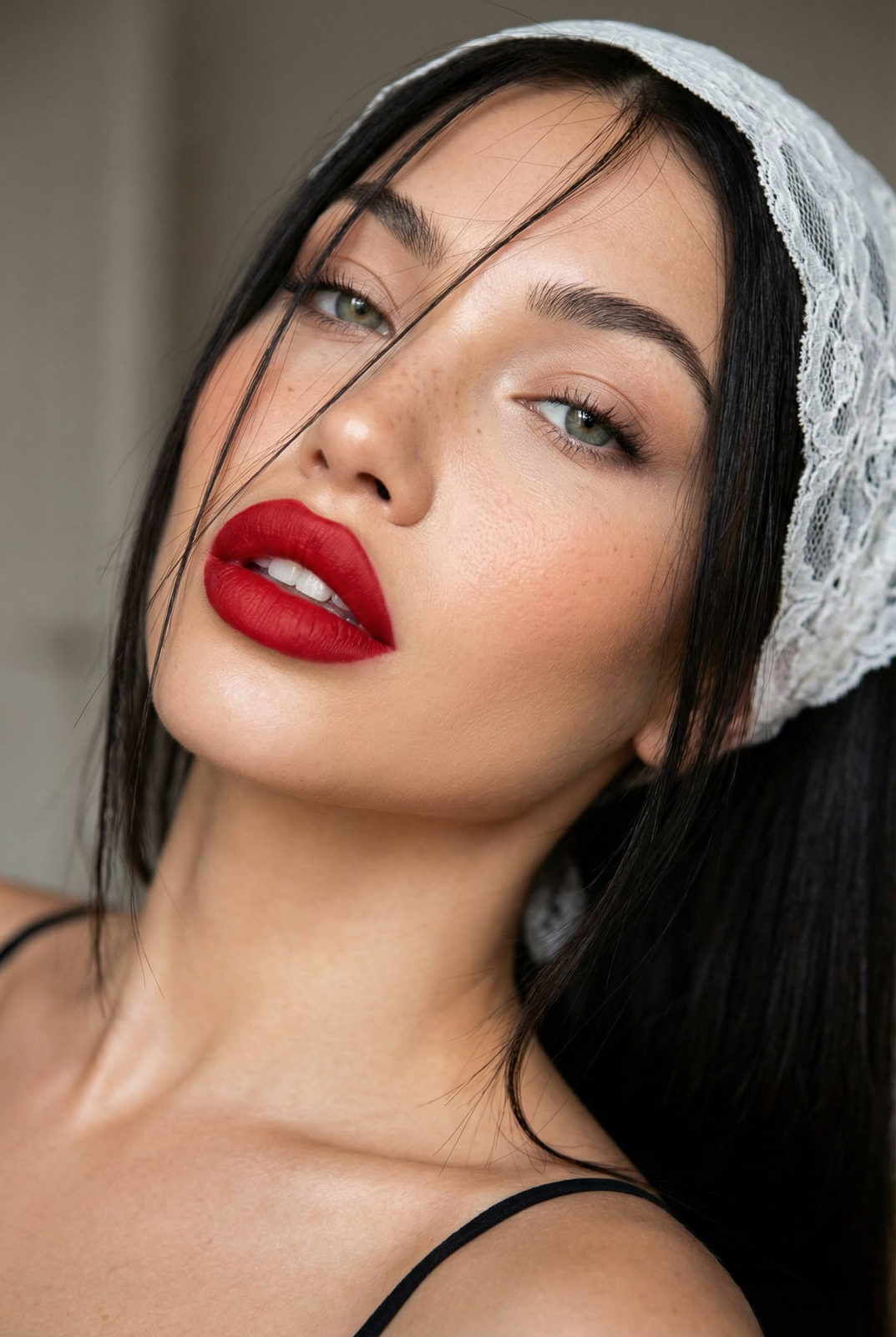 A beauty selfie of a woman with dark hair and red lips, wearing a lace headband, viewed from a dramatic angle.