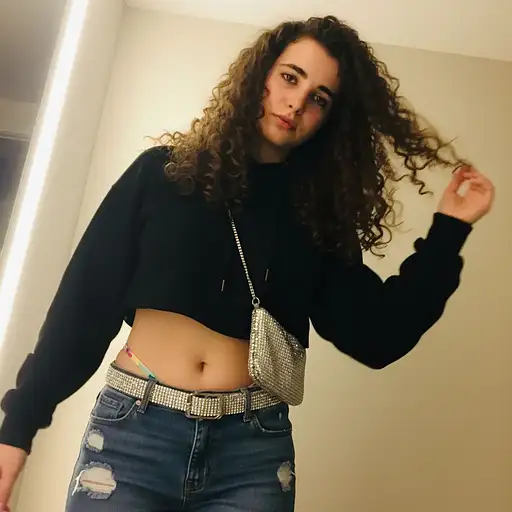 A grainy, off-center, low-quality photo of a 20-year-old baddie wearing a cropped hoodie and low-rise jeans.