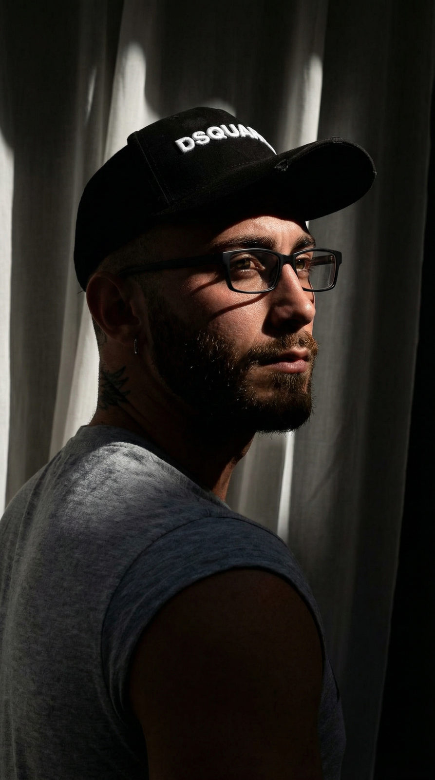 A portrait of a man with dramatic chiaroscuro lighting, showcasing deep shadows and illuminated cheekbones.