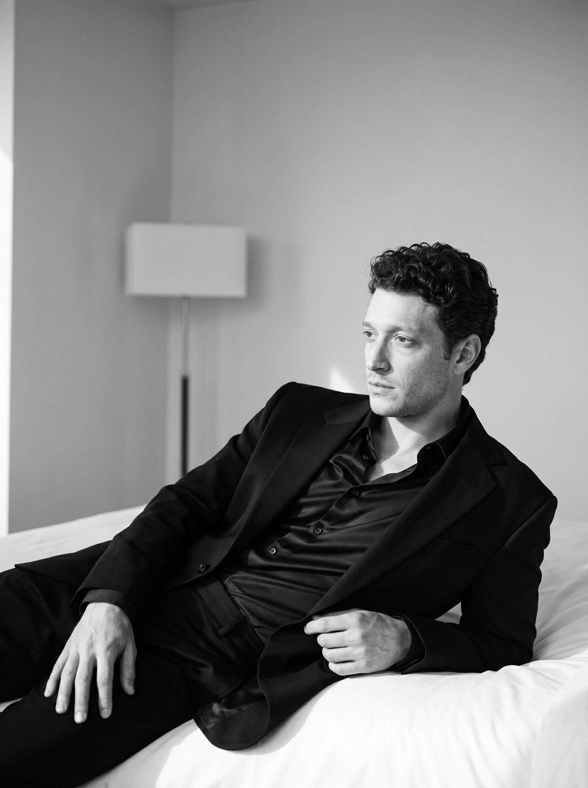 Black Suit Reclines On Hotel Bed