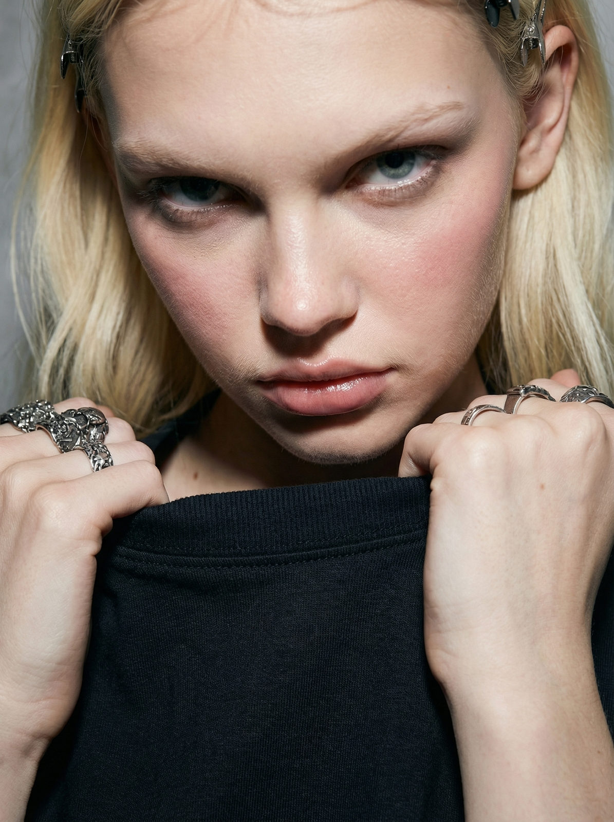 Ultra-realistic fashion portrait of a young girl in a cotton t-shirt, leaning close to the camera against a concrete wall, showcasing natural skin texture and soft lighting.