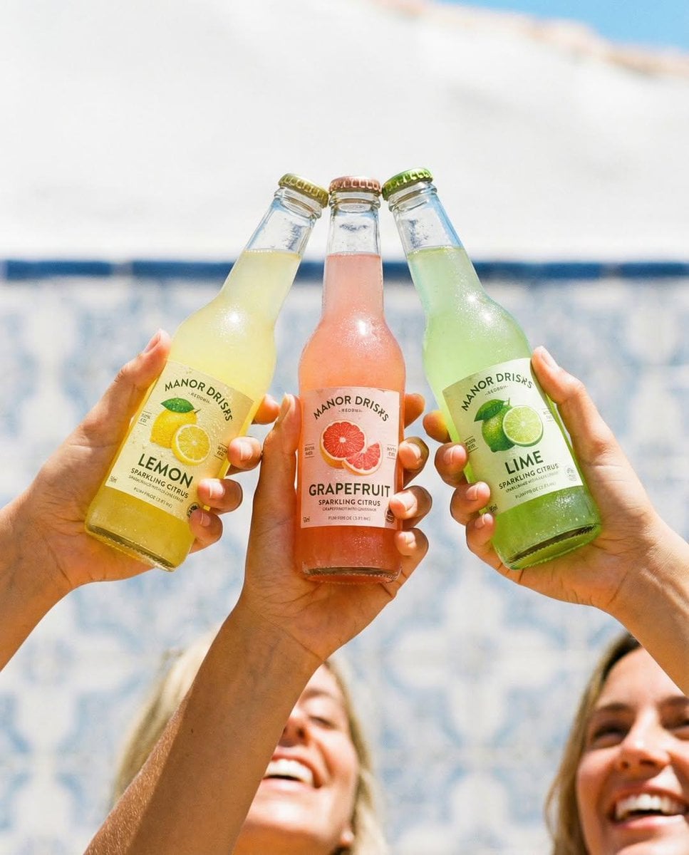 Hands Clinking Soda Bottles Bright Sunny Outdoor Setting