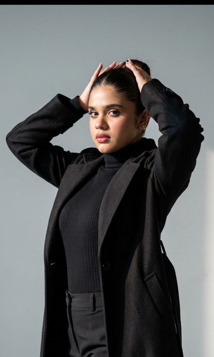 Medium Posing Against Solid Light Gray Studio Wall Is Wearing