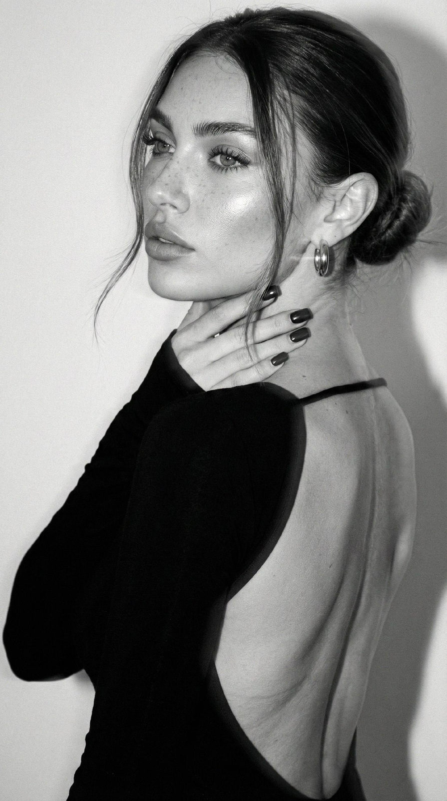 Close-up of a beautiful girl from the back in a fitted black dress with a double exposure effect.
