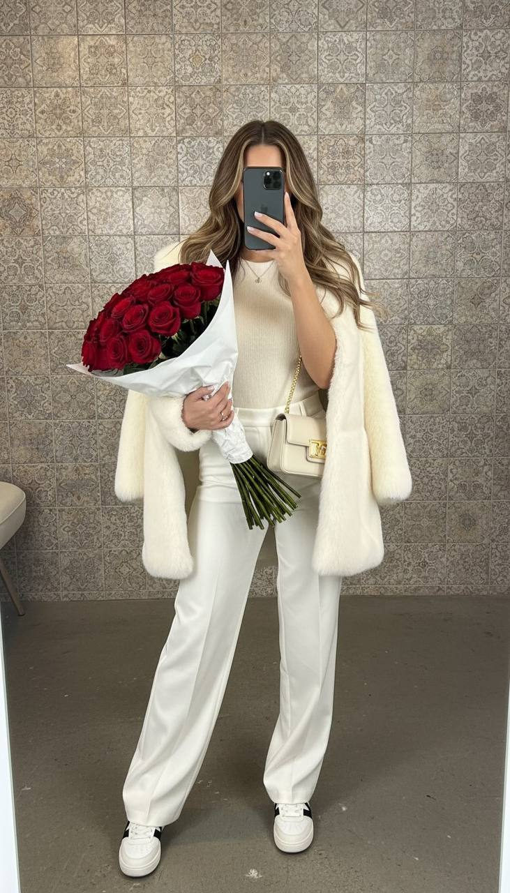 Hyper-realistic mirror selfie of a woman indoors against patterned wall, holding bouquet and smartphone.