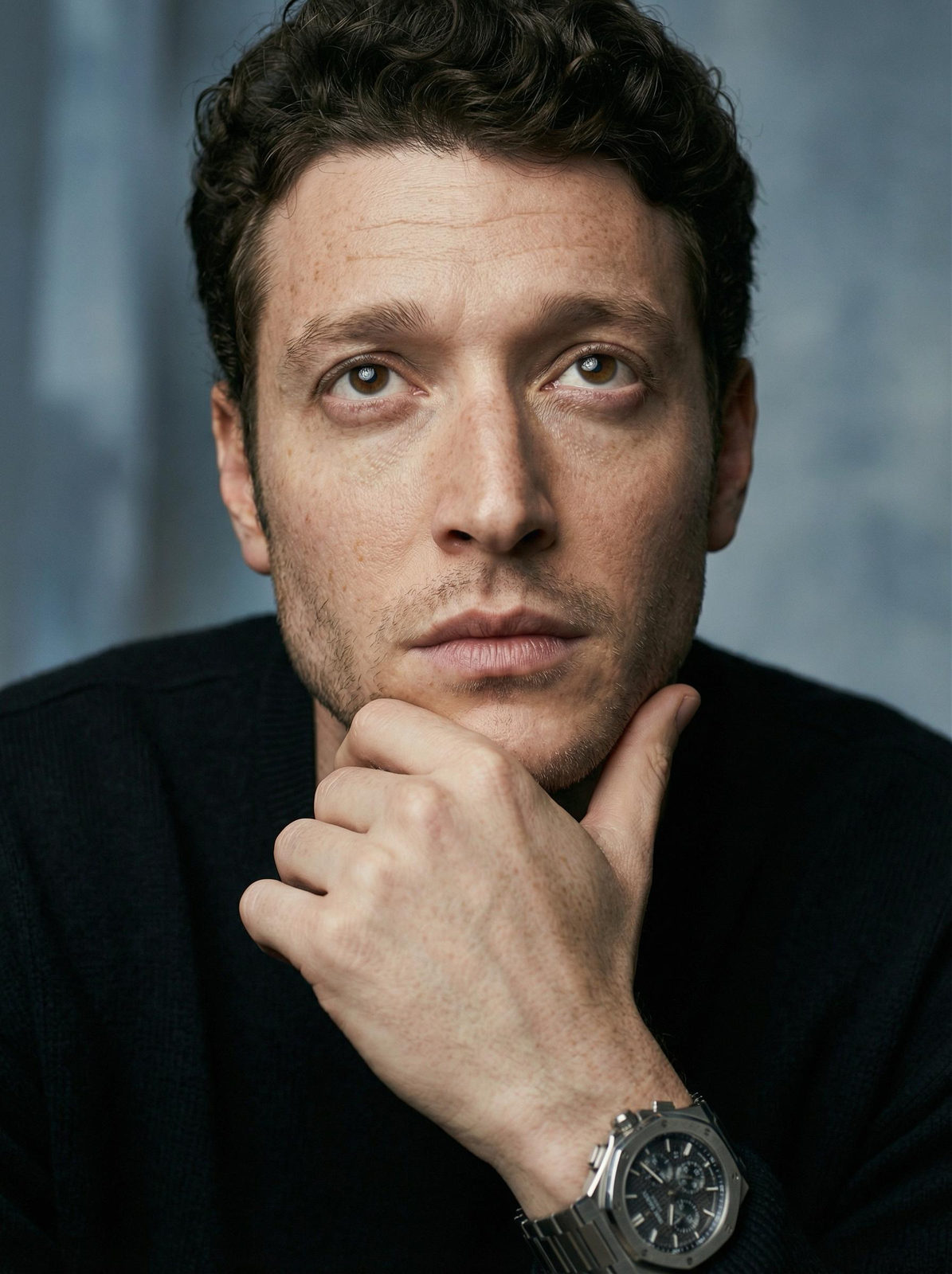 Close-up of a man's face with soft light highlighting his features and an abstract, blurred background.