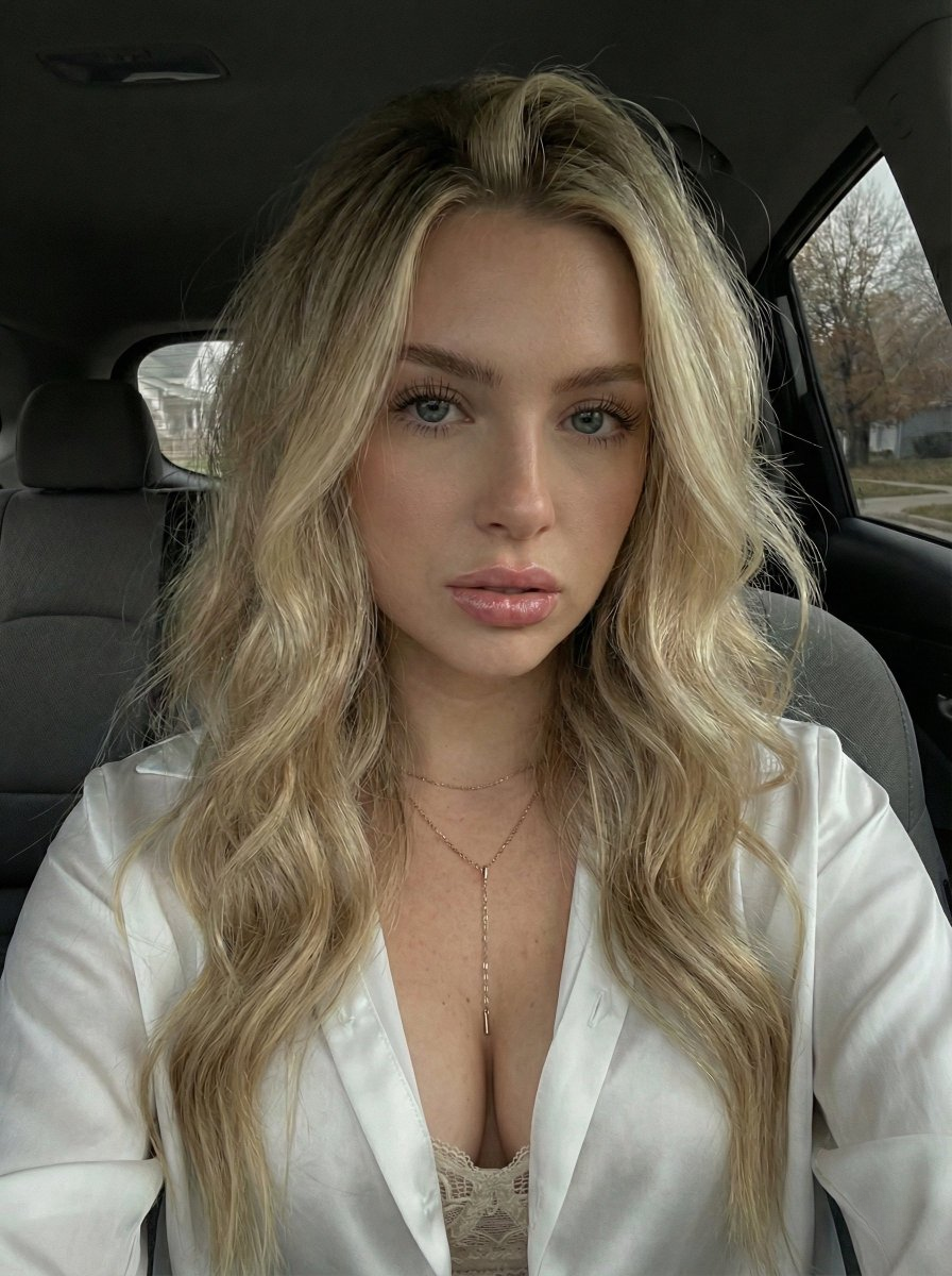 Close-up selfie portrait of a young woman with blonde hair and blue-grey eyes, looking thoughtfully out of a car window.
