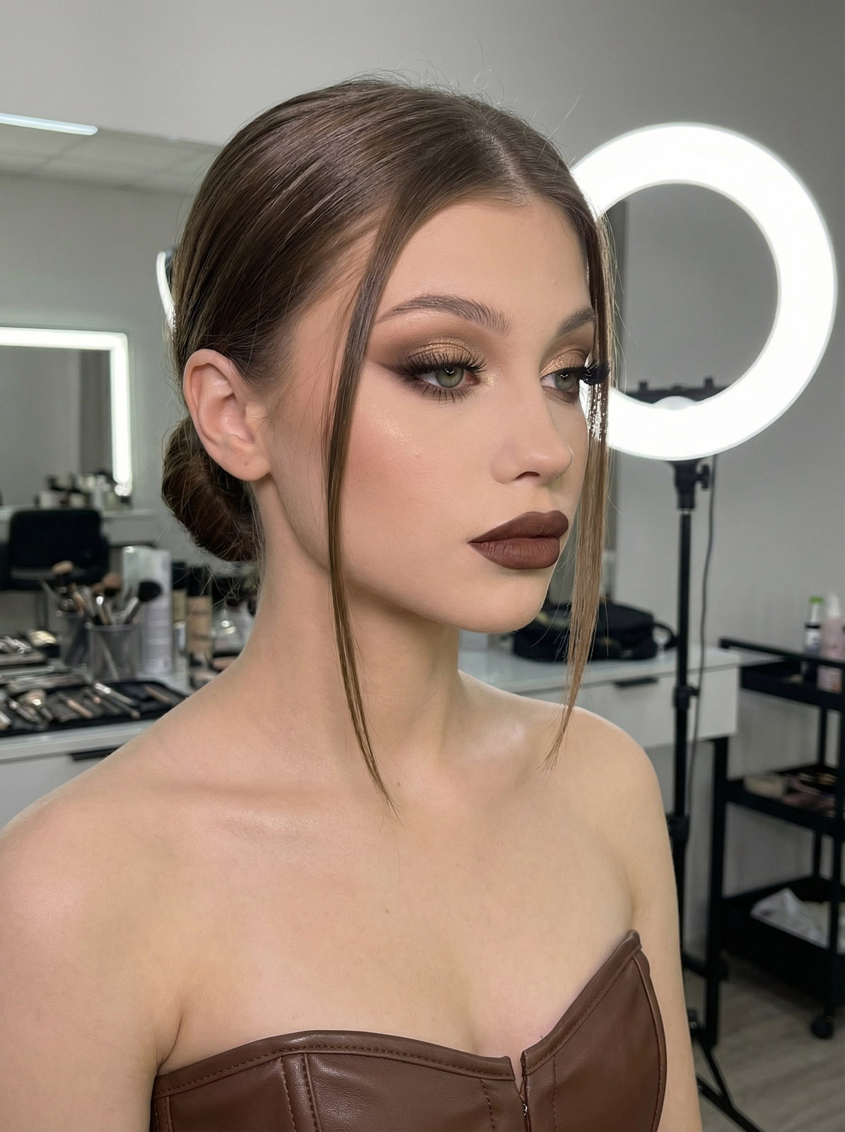 Close-up portrait of a woman with ideal evening makeup featuring smoky eyes and matte lips, seated in a beauty salon.