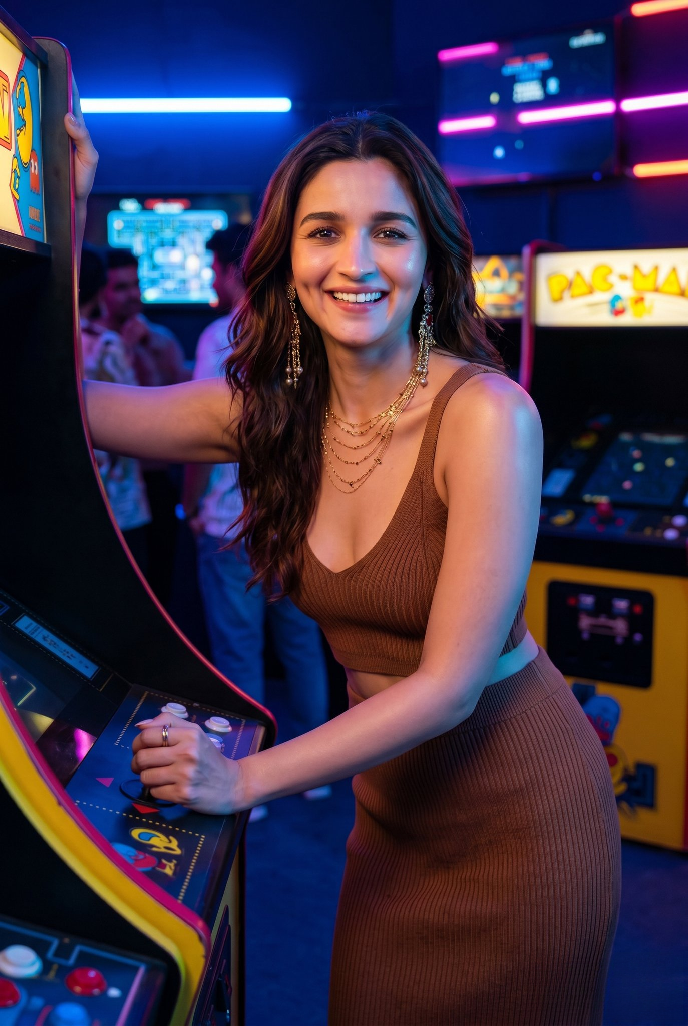 Woman in brown ribbed bikini top and bottoms poses by arcade machine, large gold earrings and necklace.