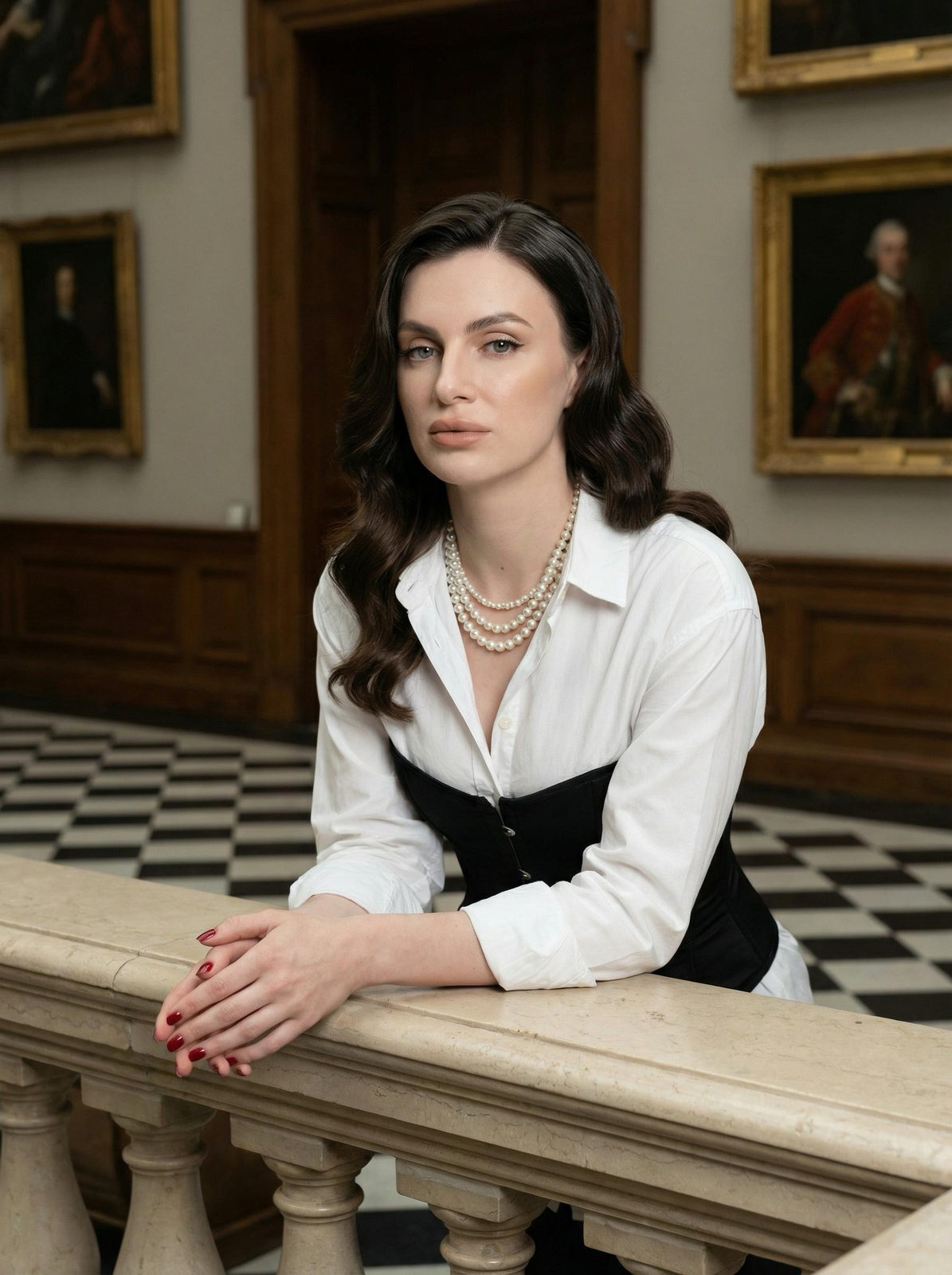 A woman with large waves hairstyle poses elegantly by a stone balustrade in a classical gallery.