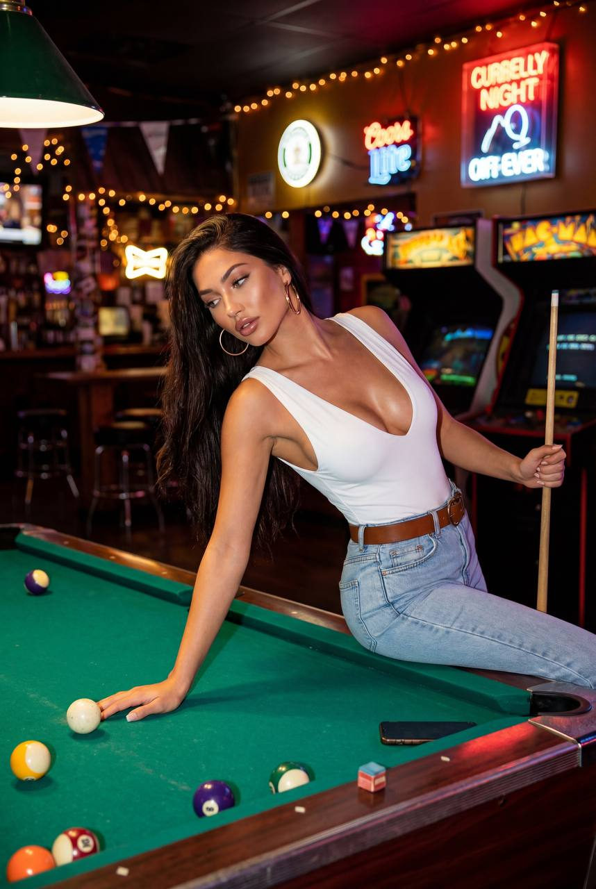 A woman in a fitted tank top poses gracefully over a pool table in a dimly lit bar, with vibrant neon lights in the background.