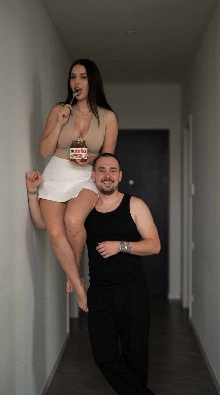 Two People In Interior Corridor With Dark Door