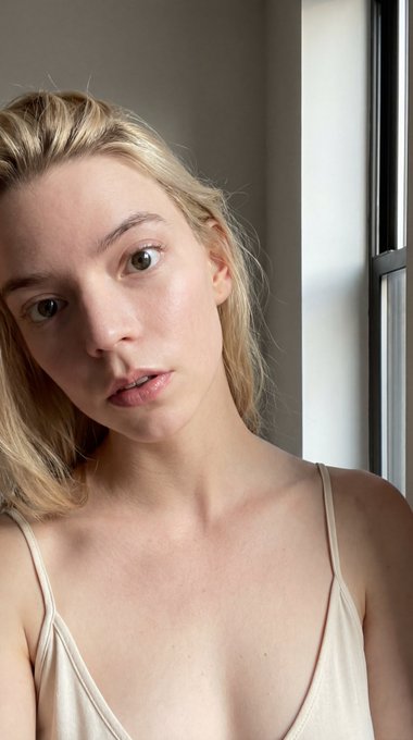 Close-up selfie of a woman with natural light from window, relaxed pose and soft expression, subtle textures visible.