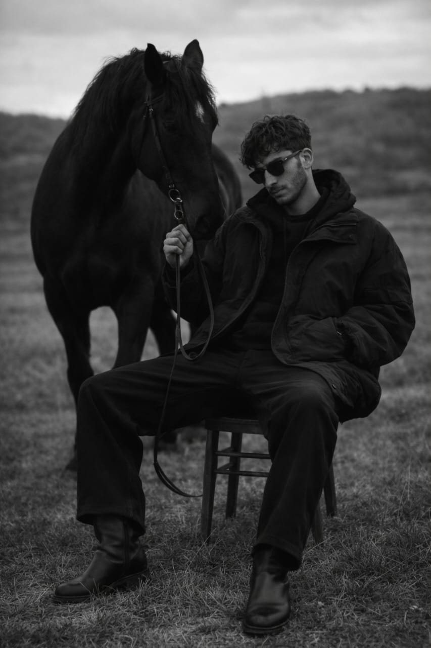 Seated In Field Holding Horse Lead