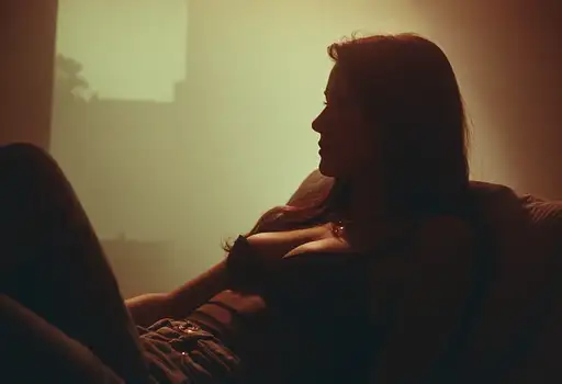 A sexy woman in a tight top and jeans, relaxing in her yard, illuminated by a soft diffused glow.