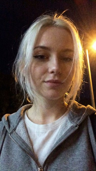 Close up night selfie of a woman in soft lighting with porcelain skin textures.