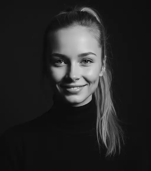 Headshot portrait of a young blonde woman with a ponytail wearing a black turtleneck, looking directly at the camera.