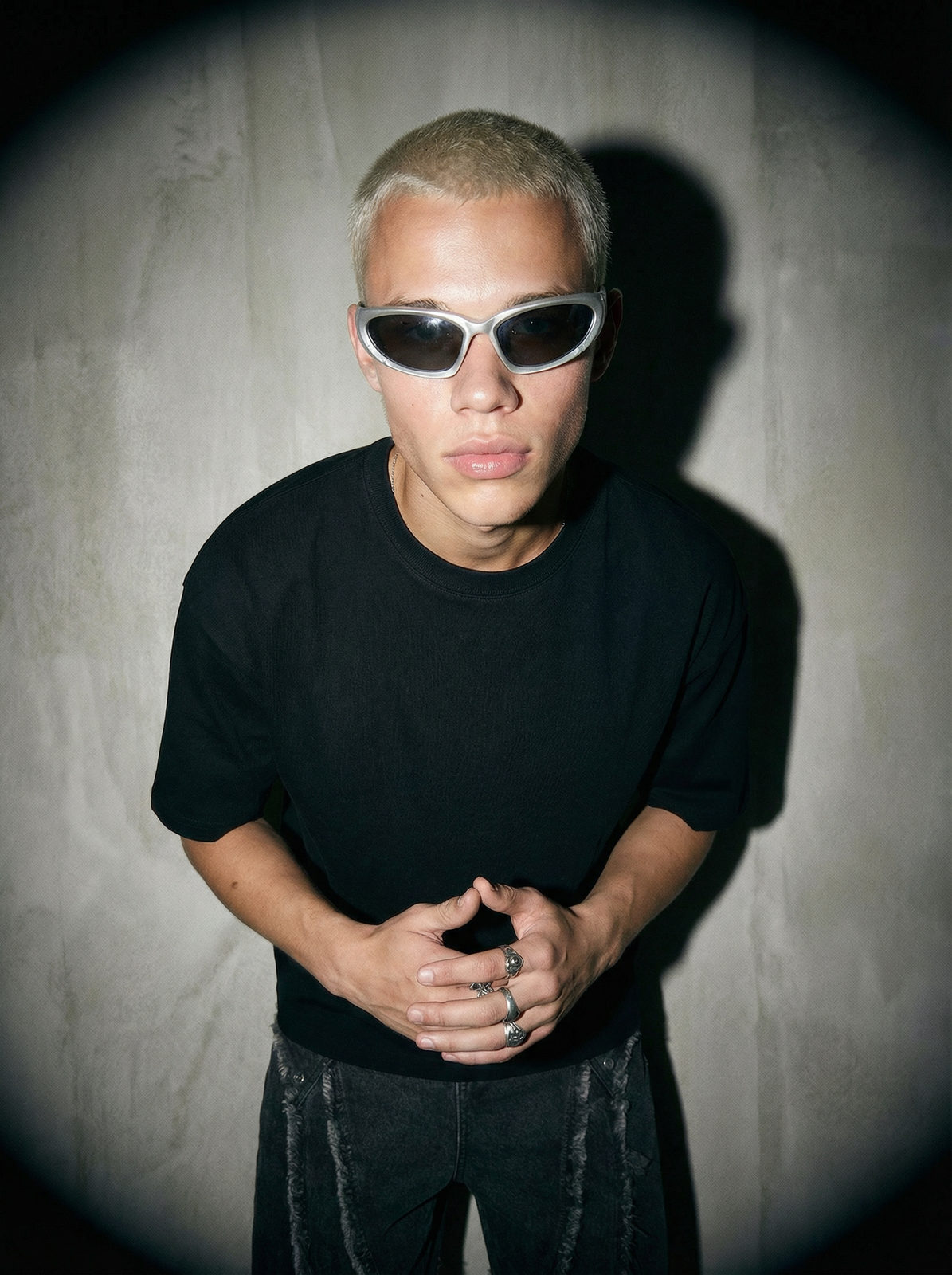 Ultra realistic fashion portrait of a young man in front of a concrete wall, capturing natural texture and dynamic lighting.