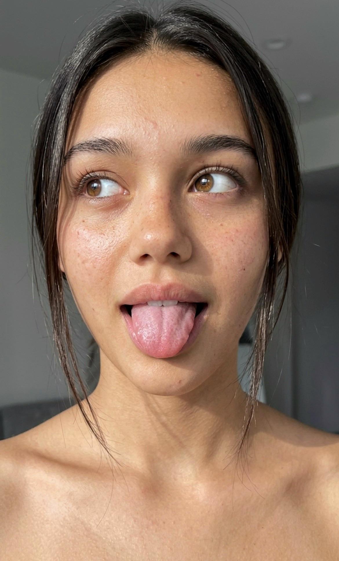 Close-up portrait of a person with dark hair, playfully sticking tongue out, showcasing natural skin tones and textures.