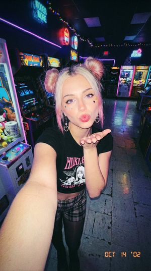 A Y2K-inspired selfie taken in a vibrant arcade setting, showcasing grunge fashion.