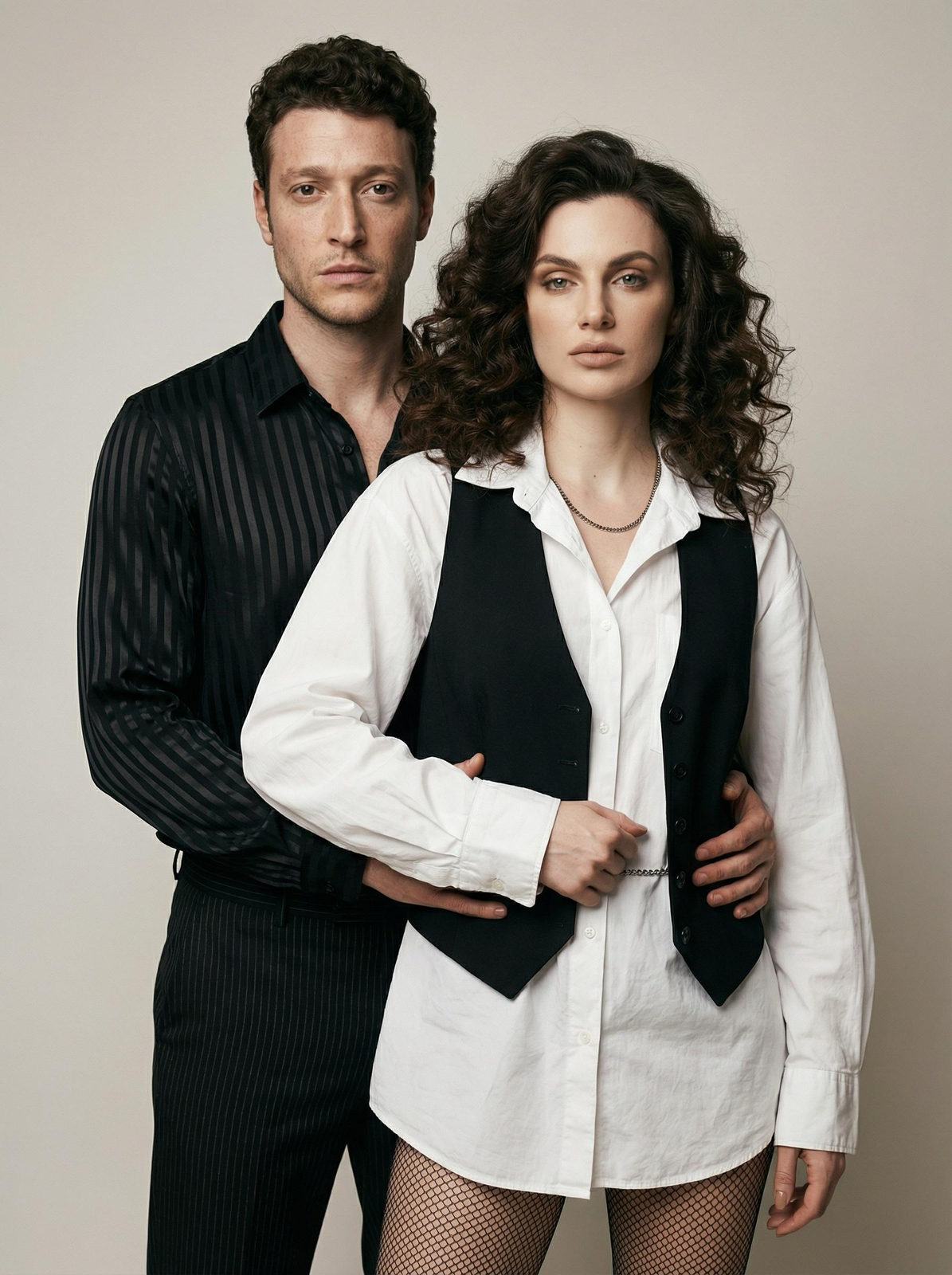 A couple in a minimalist studio, showcasing realistic fashion styles with neutral tones and soft lighting.