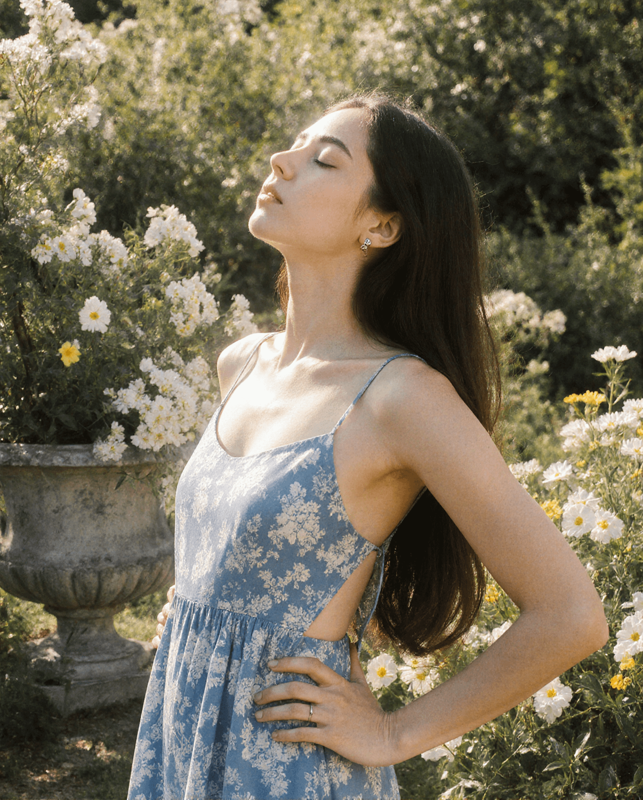 Person in a blue sundress standing in a sun-drenched garden with wildflowers.
