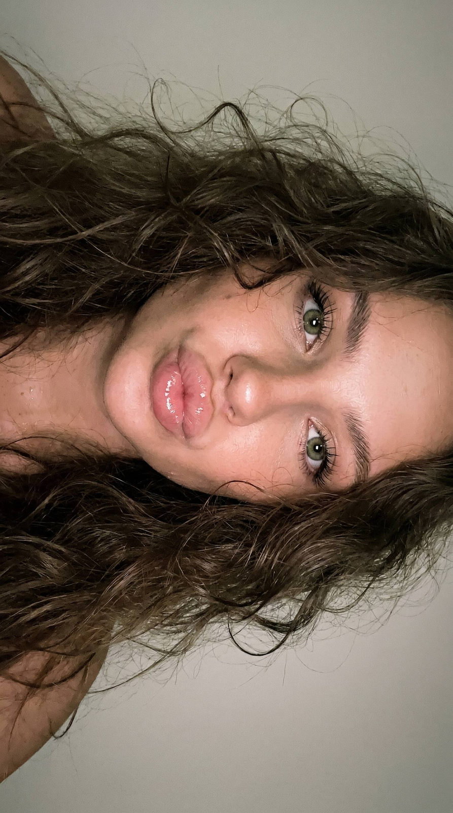 Extreme close-up of a beautiful girl's playful kiss, featuring large shiny eyes and voluminous dark curls.