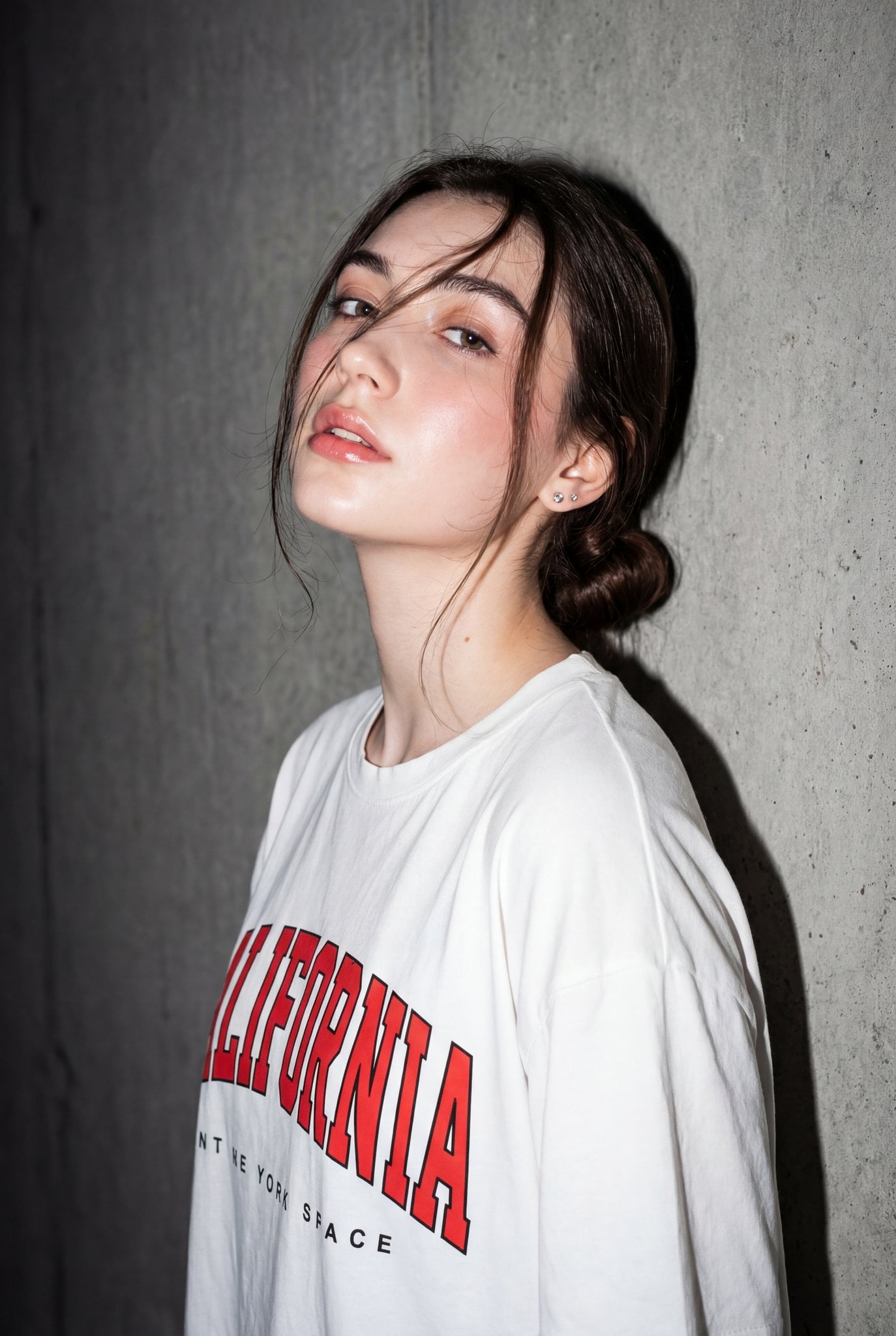 Editorial-style portrait of a woman against a textured gray concrete wall with dramatic flash lighting.