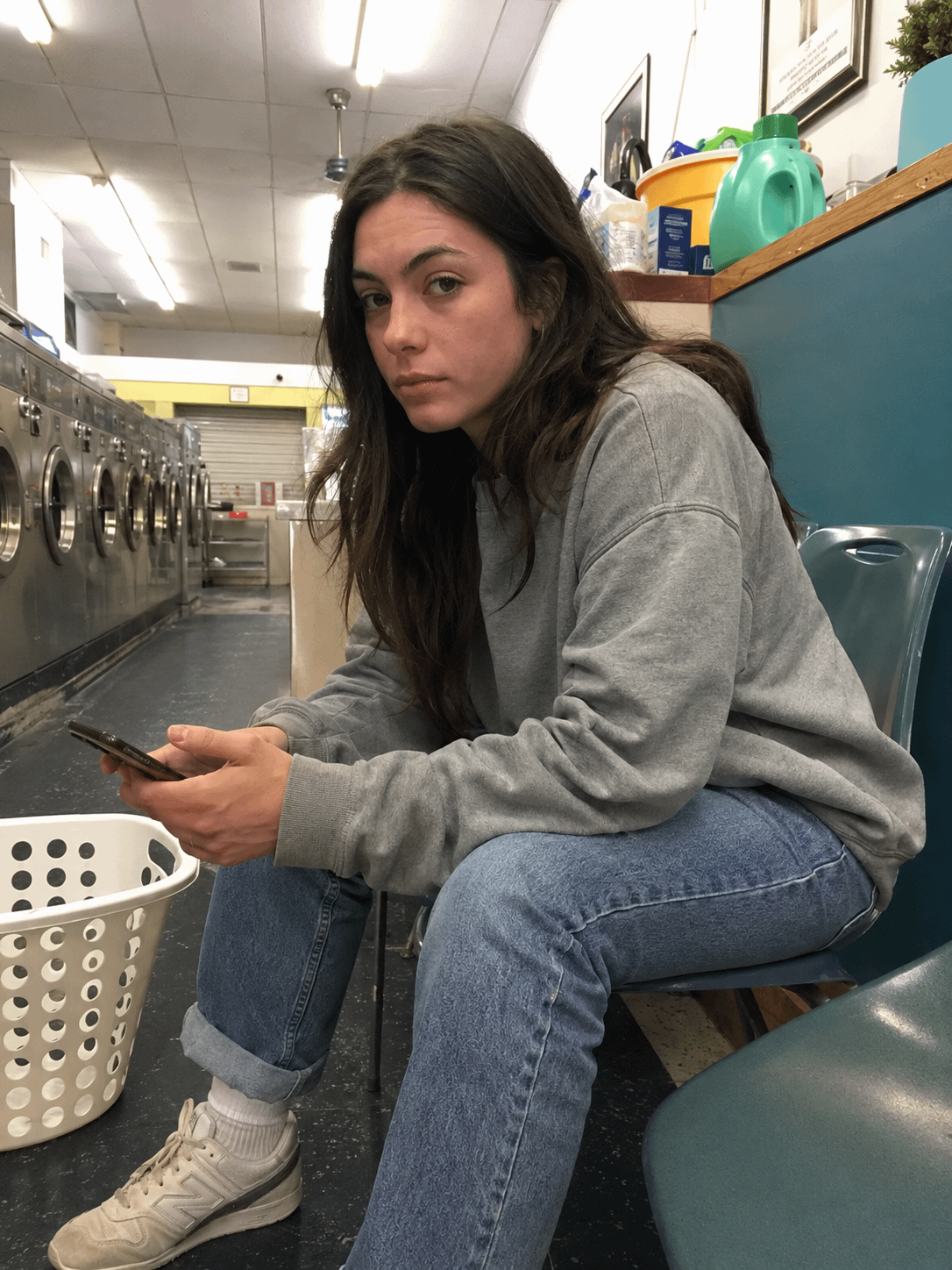 Laundromat Scene Person In Gray Sweatshirt Holding Phone