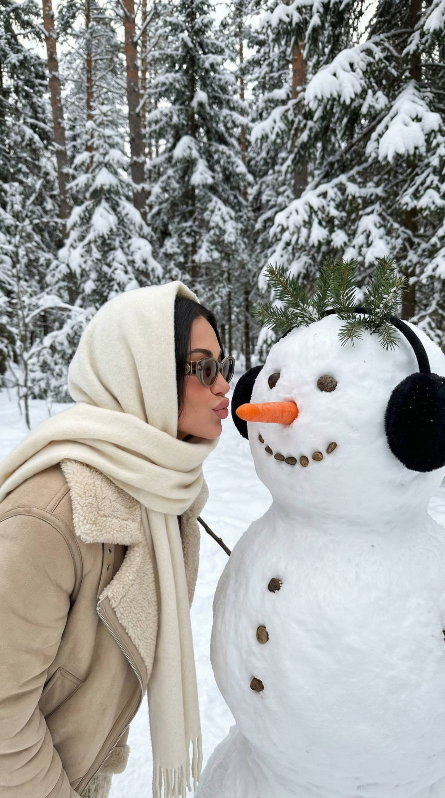 A playful winter portrait of a person in a snow-covered forest, leaning towards a snowman, embodying a near-kiss moment.