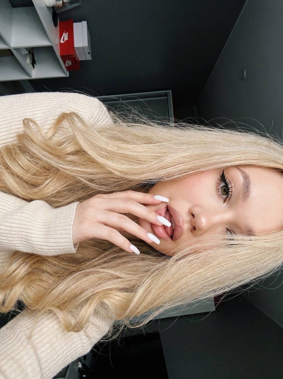 Close-up of a girl's long, voluminous hair with delicate curls and makeup, taken in a bright setting.