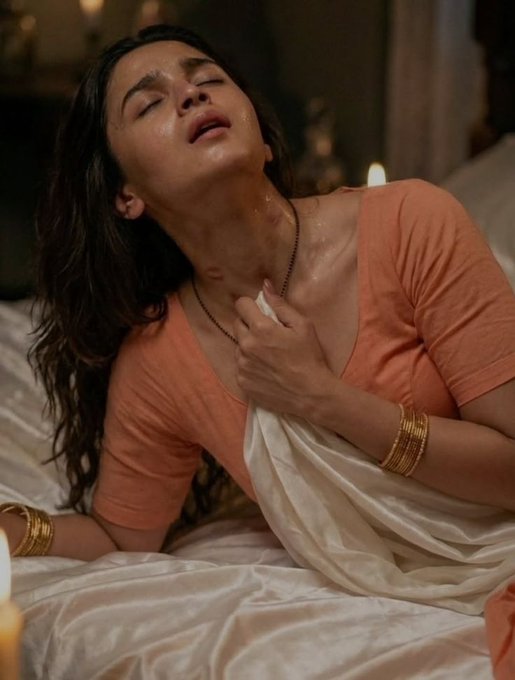 Ultra-realistic portrait of a young Indian woman reclining on a bed with a warm expression in a softly lit room.