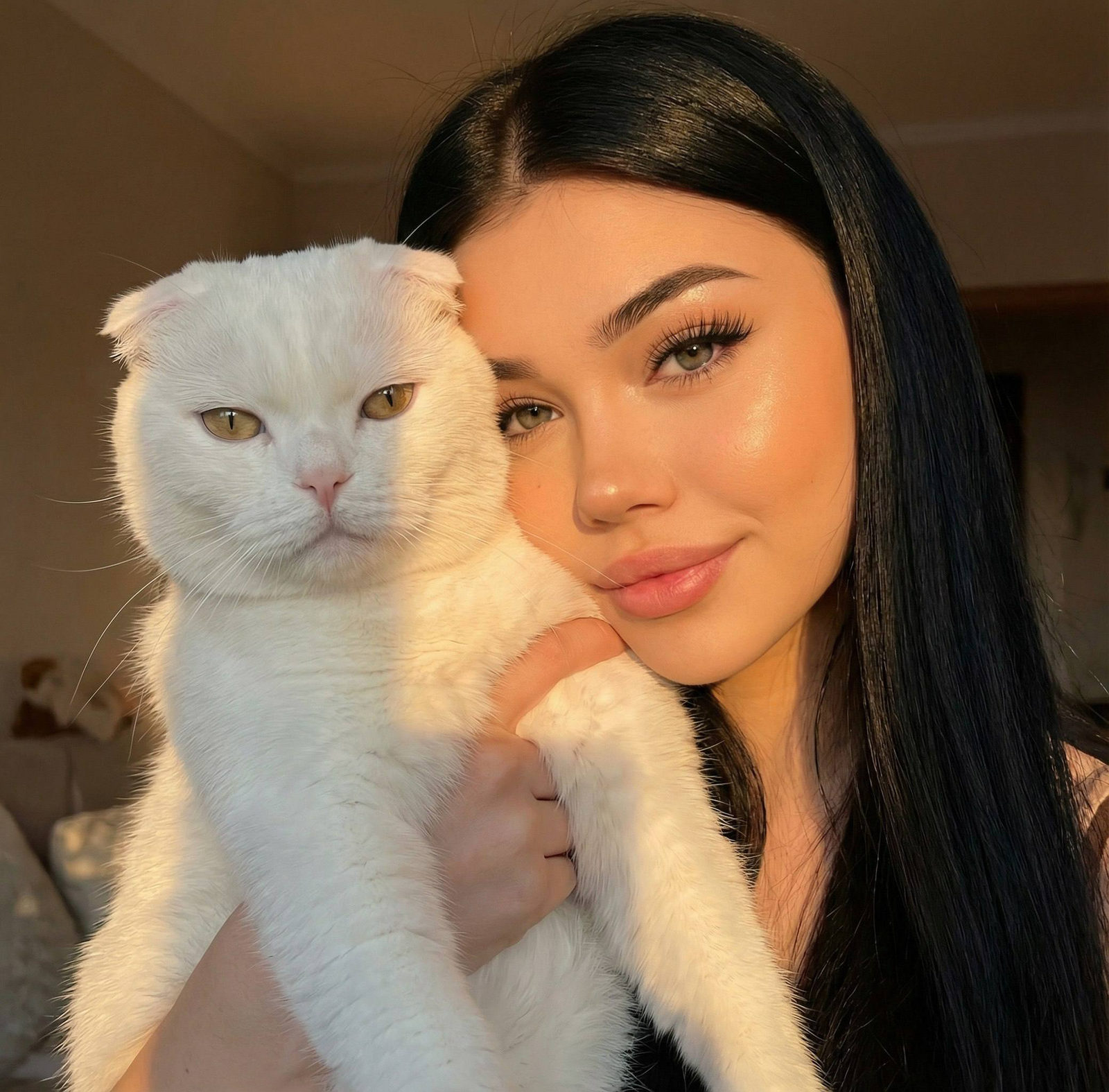 Close-up portrait of a woman with long hair holding a lop-eared cat in warm sunset lighting, showcasing soft smiles and furry textures.
