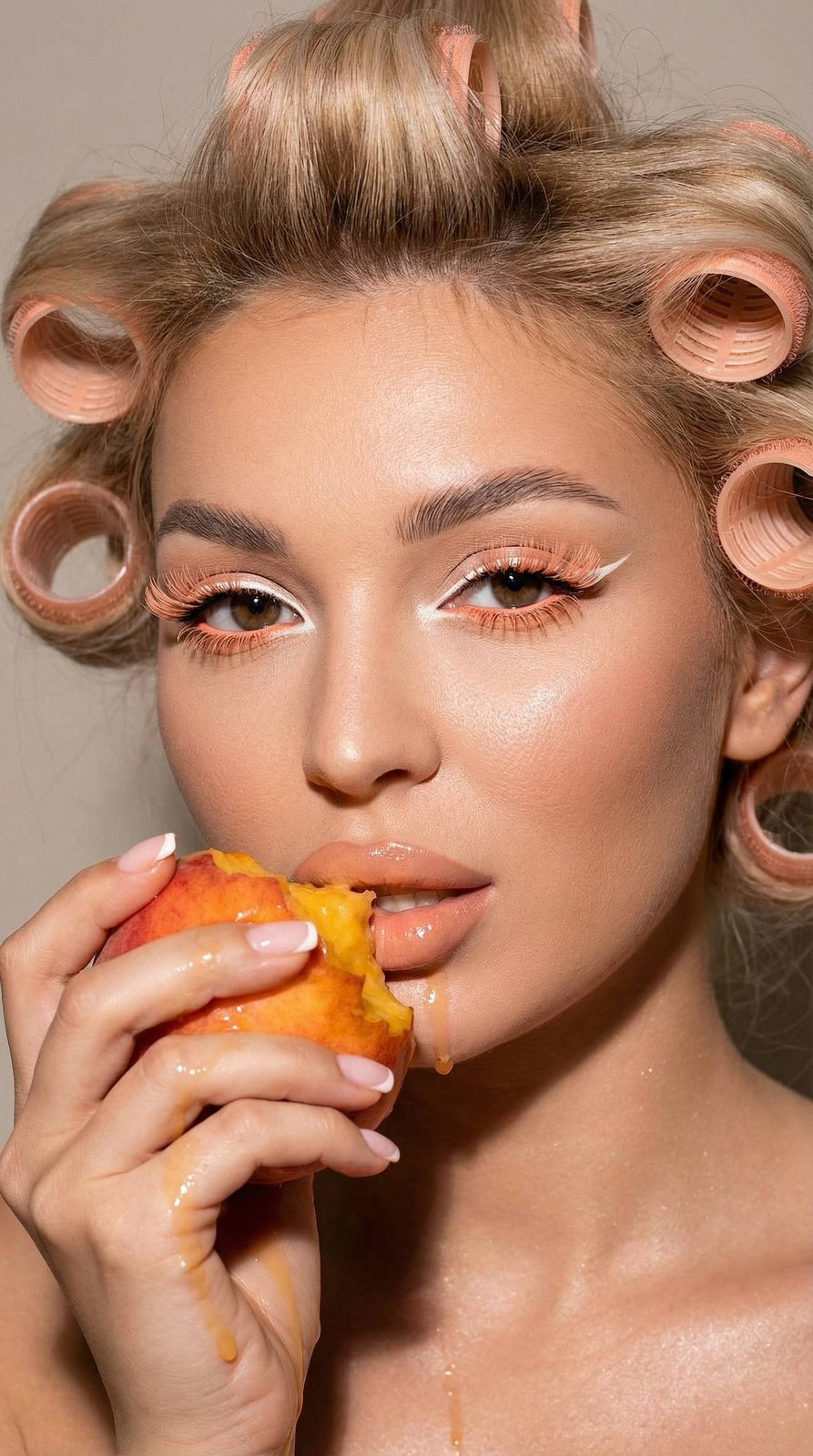 Close-up portrait of a woman with playful peach makeup, holding a juicy peach near her lips, lit dramatically with flash.