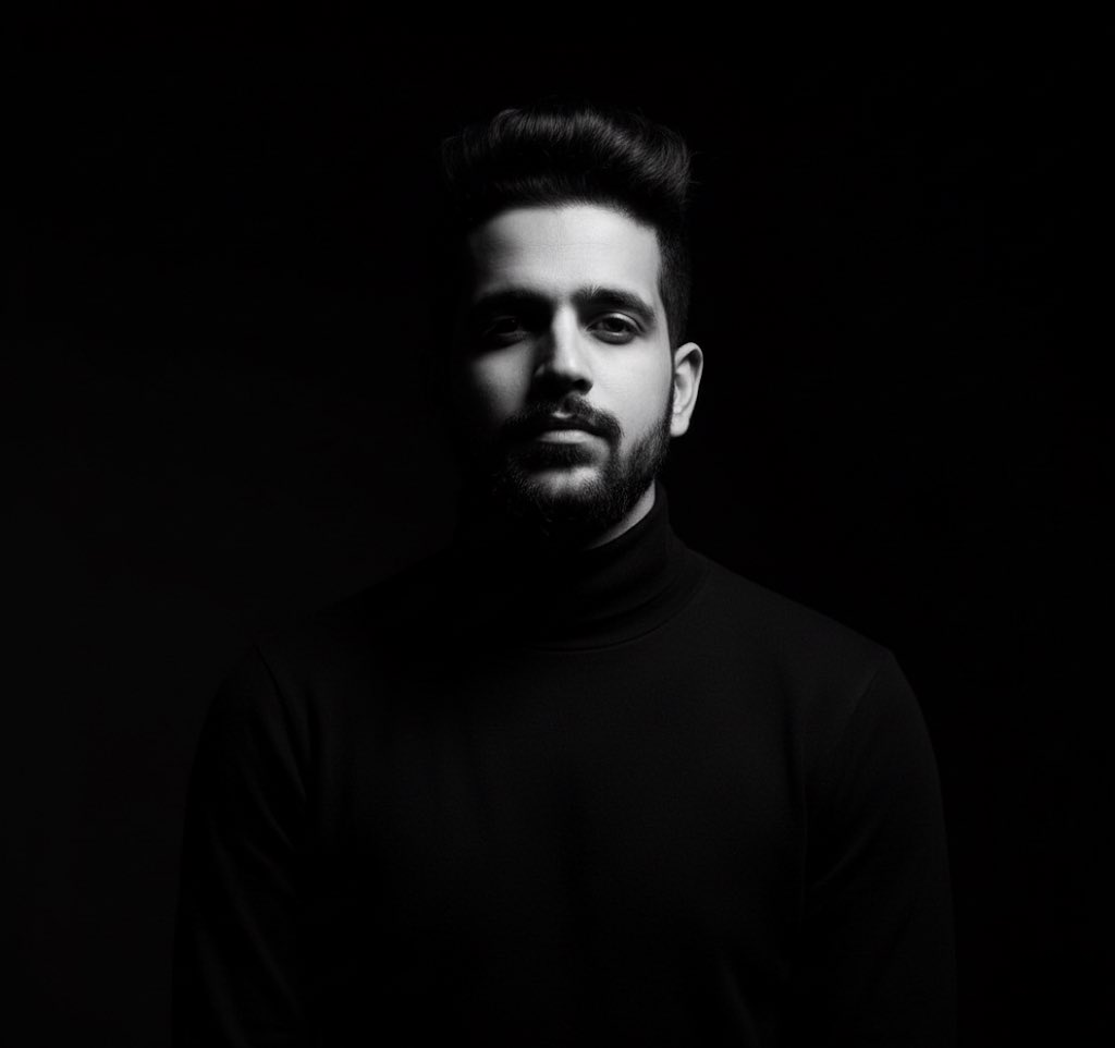 A high-contrast black-and-white side-profile portrait of a person emerging from darkness with a contemplative expression.
