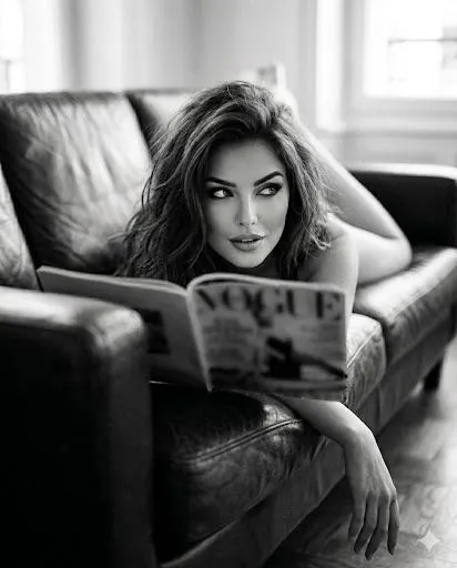 Black And White Prone On Leather Sofa Holding Vogue Magazine