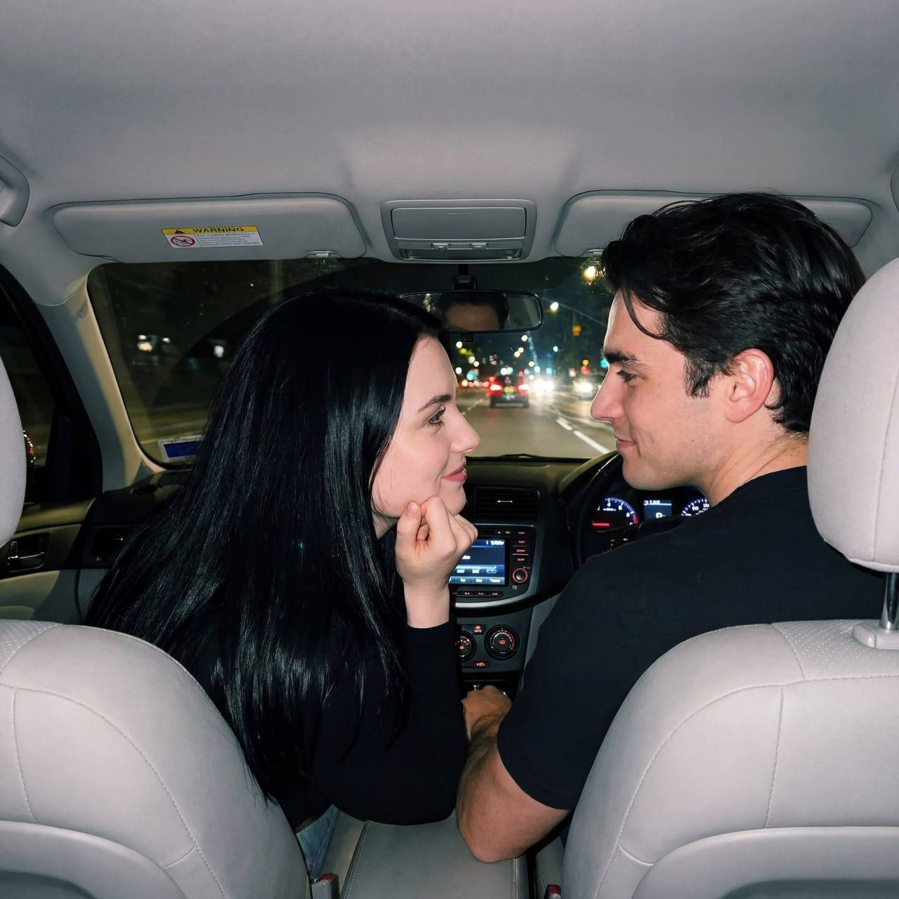 A couple in a car at night, gazing at each other lovingly with soft flash lighting.