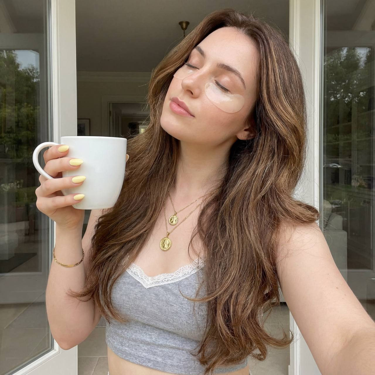 A woman with long brunette hair holds a mug near her face, radiating a serene morning glow with soft lighting.
